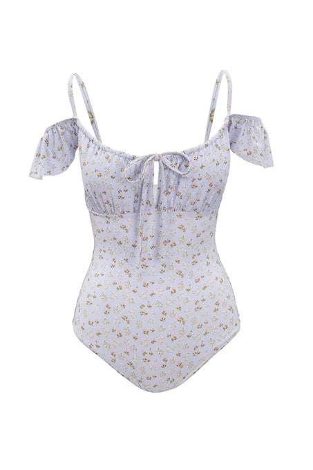 The Maise One Piece by Ivy City Co features a blue ditsy floral print with small yellow blooms, off-shoulder ruffled sleeves, and a front tie at the bust. This stylish swimsuit is shown on a white background.