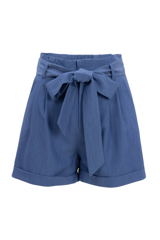 The Maria Shorts in Chambray by Ivy City Co feature a wide waistband, front pleats, cuffed hems, and a matching fabric belt tied in a bow—stylish blue womens shorts for effortless style.