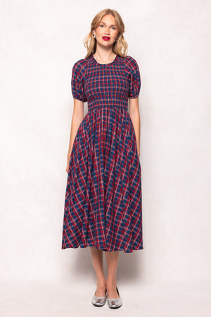 Woman wearing a red and blue plaid dress against a white background