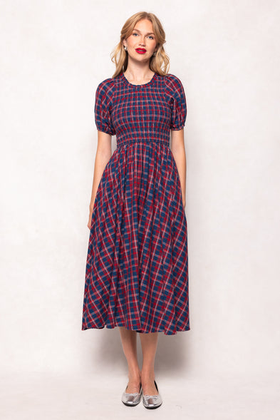 Woman wearing a red and blue plaid dress against a white background