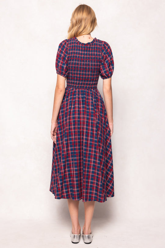 Woman wearing a red and blue plaid dress against a white background