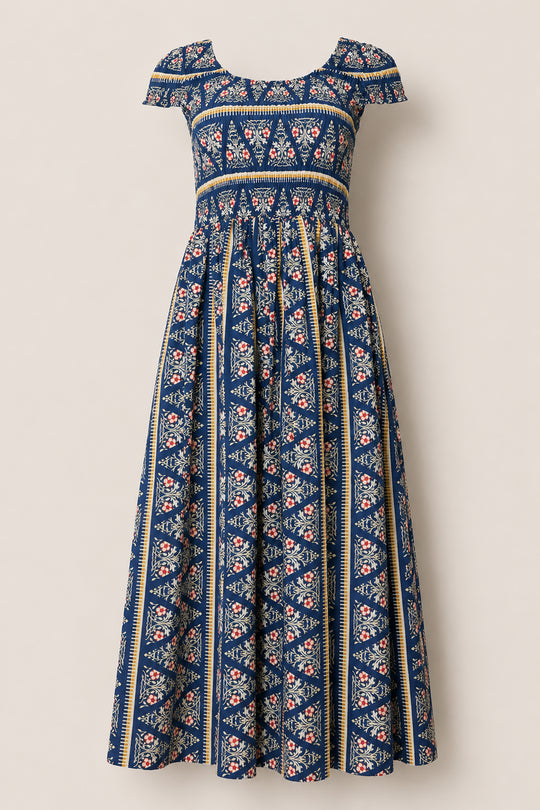 Introducing the Marlow Cap Sleeve Dress in Navy Fleur by Ivy City Co—a blue maxi dress with cap sleeves and a scoop neckline, adorned with a vibrant mix of floral and geometric patterns. The pleated, flowing skirt offers a vintage-inspired bohemian look, while its smocked bodice ensures comfort and flexibility for all-day wear.