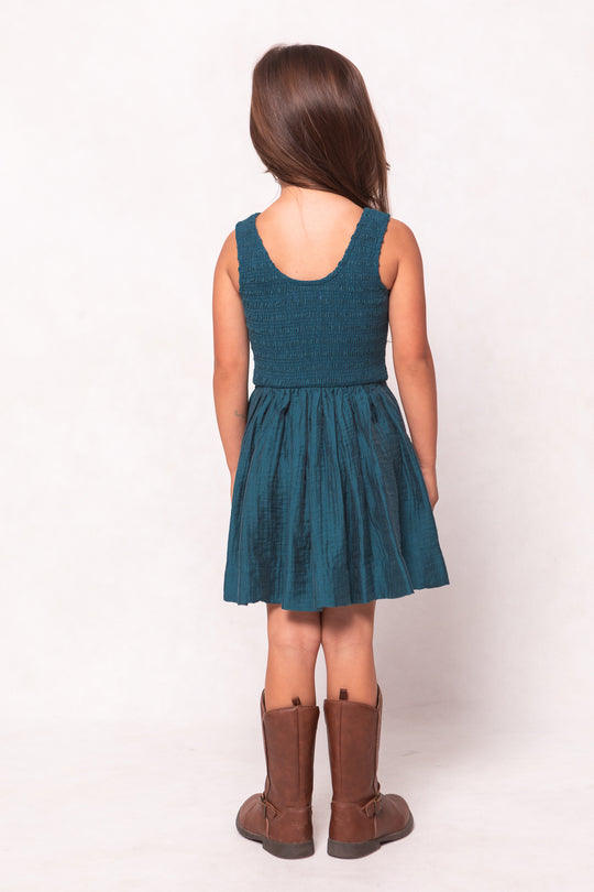 Girl wearing a teal dress and brown boots on a white background