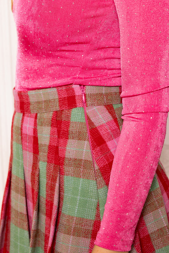 Close-up of a pink top and plaid skirt with a blurred background