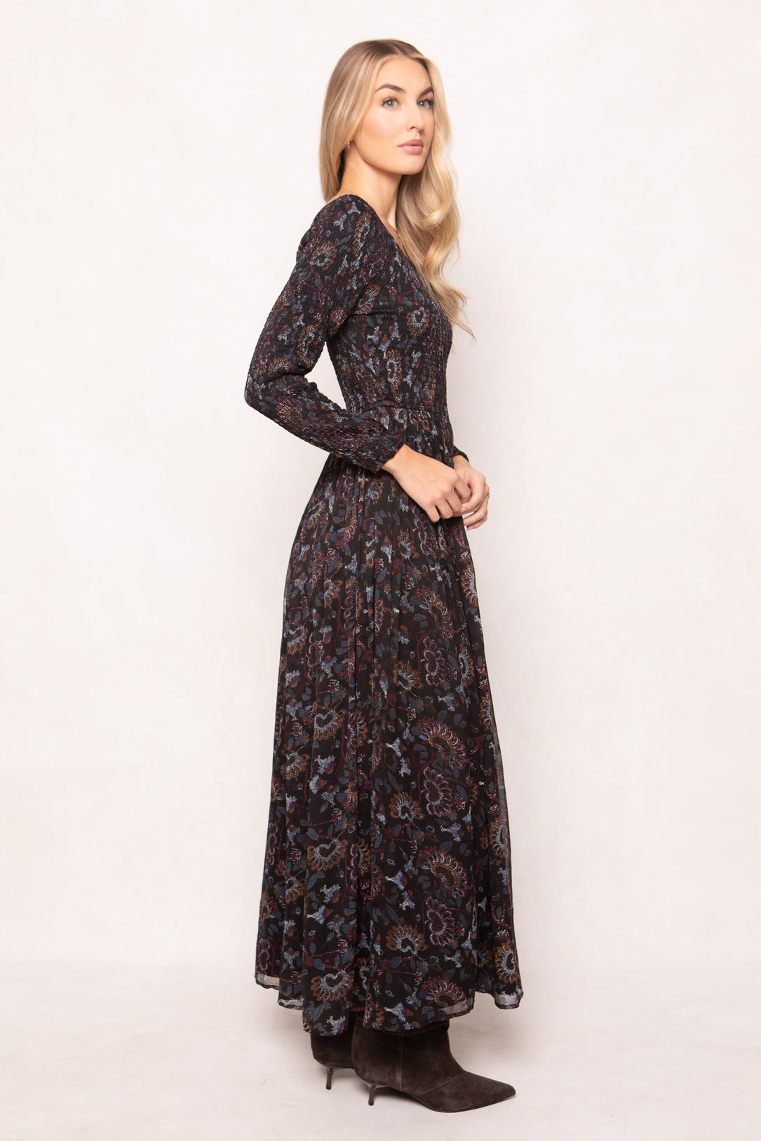 Woman wearing a long, dark floral-patterned dress against a white background
