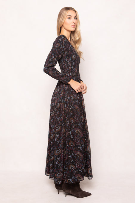 Woman wearing a long, dark floral-patterned dress against a white background