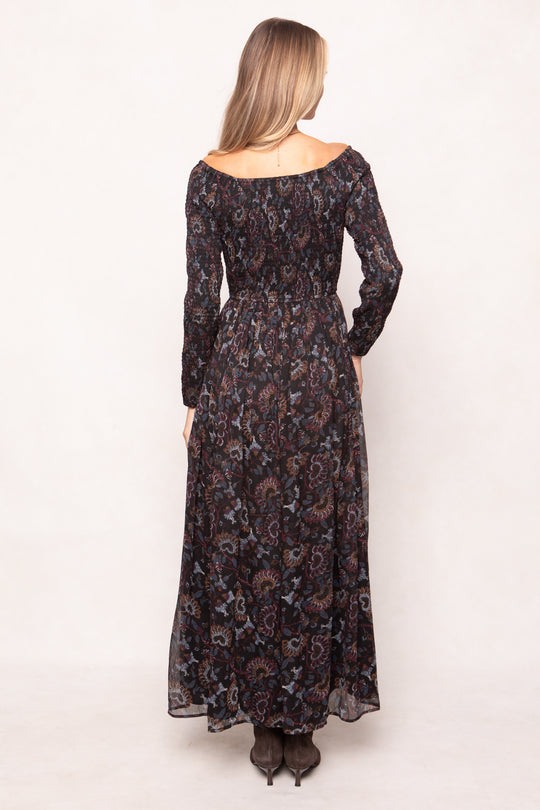 Woman wearing a long floral dress with long sleeves on a white background