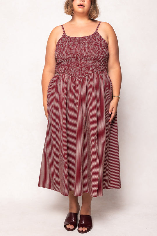 Woman wearing a maroon and white striped dress on a white background