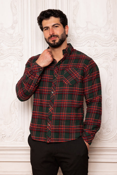 Man wearing a red and green plaid shirt against a white textured wall