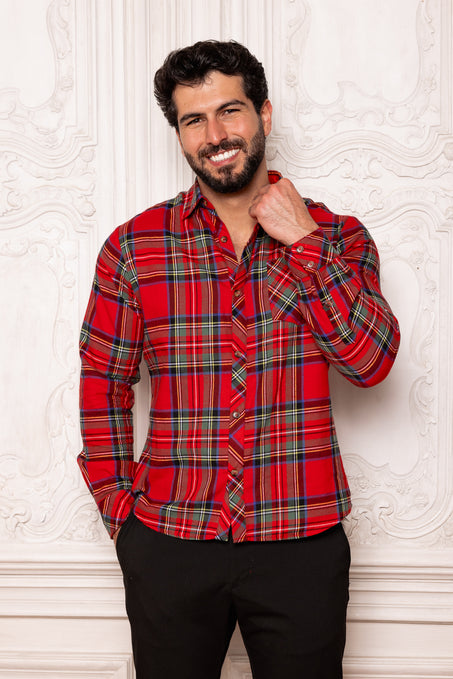 Man wearing a red plaid shirt against a textured white wall