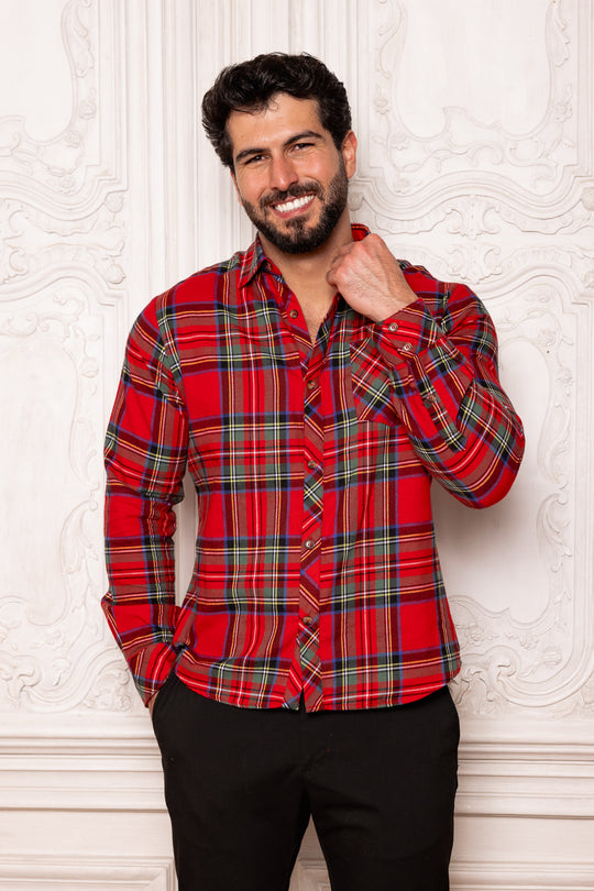 Man wearing a red plaid shirt against a textured white wall