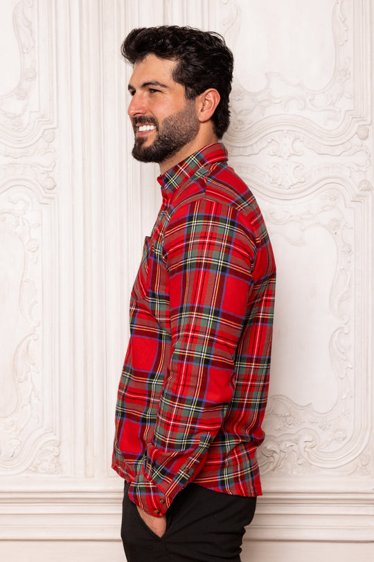 Man wearing a red plaid shirt against a white decorative wall