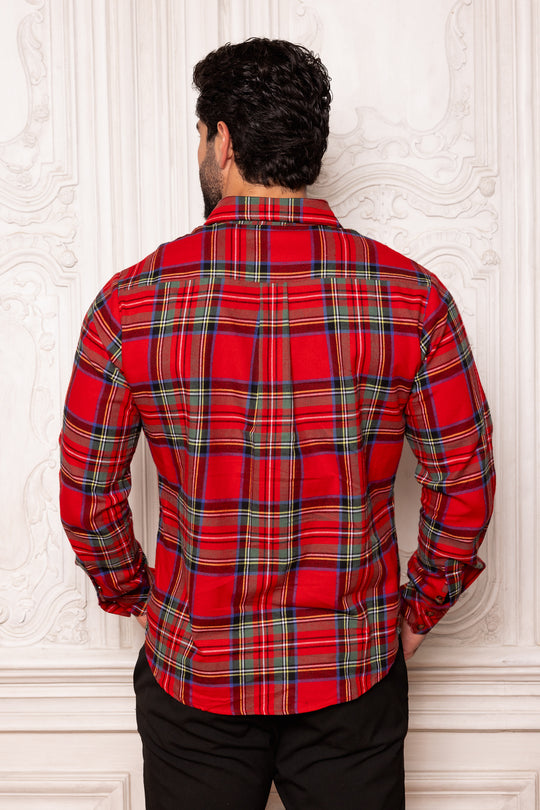 Man wearing a red plaid shirt against a white wall