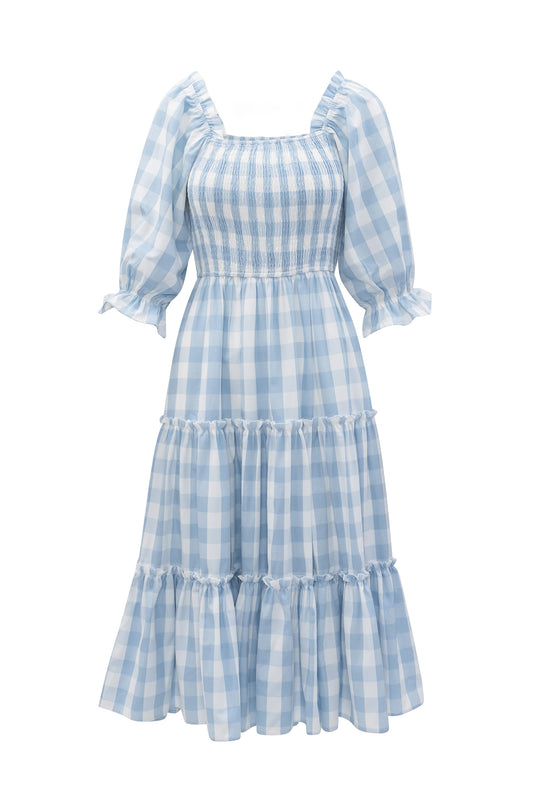 The Mia Gingham Dress in Blue by Ivy City Co features light blue and white gingham, puffed half sleeves, a smocked bodice, tiered mid-length skirt, square neckline, and ruffle details—both stylish and nursing friendly.