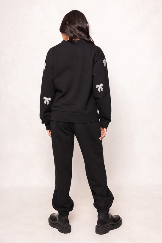 woman in a black sweatsuit against at white background