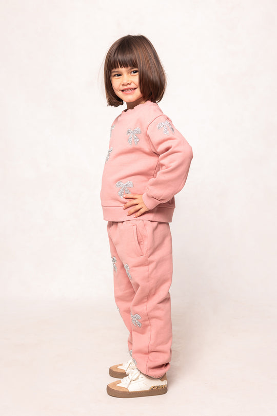 child in a pink sweatsuit against a white background