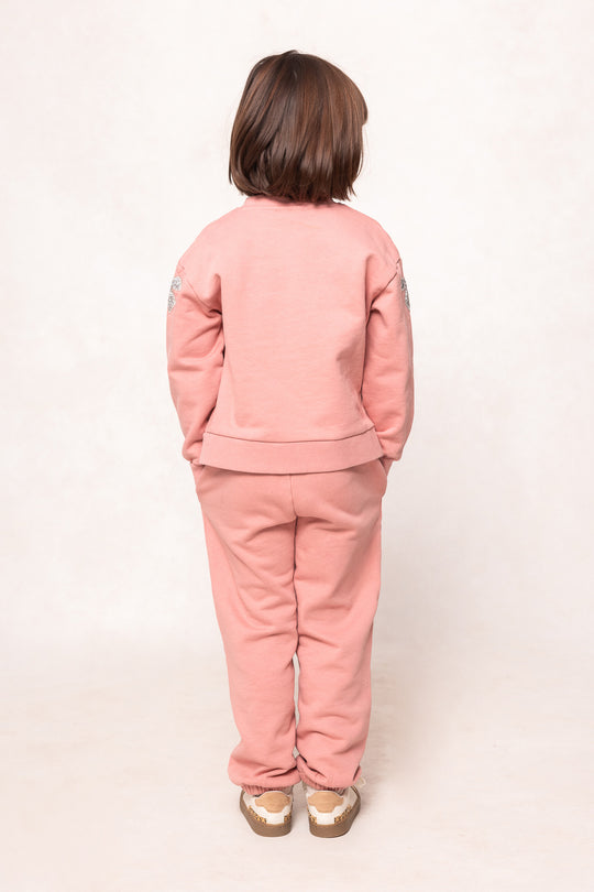 girl in a pink sweatsuit against a white background