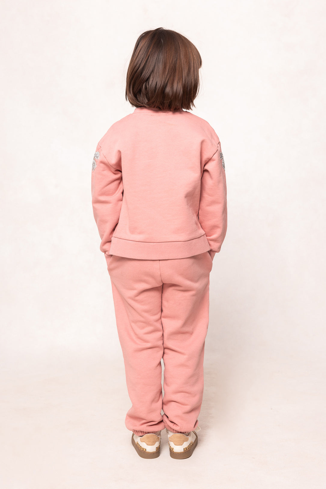 child in a pink sweatsuit against a white background