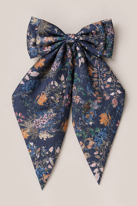 A large navy blue hair bow with long tails, featuring an intricate floral pattern in orange, pink, green, and blue on a neutral background—the perfect accessory from Ivy City Co’s Hair Bows in Midnight Autumn Bouquet collection.