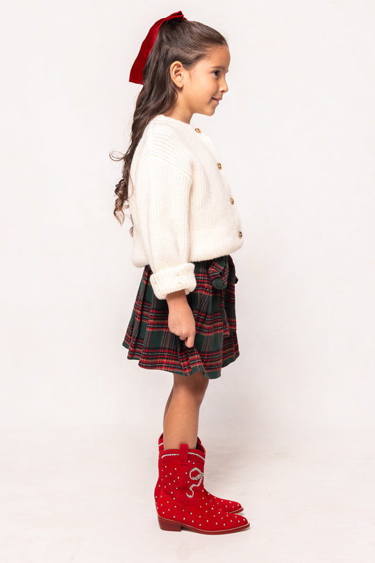 Young girl wearing a white blouse, plaid skirt, and red boots on a white background