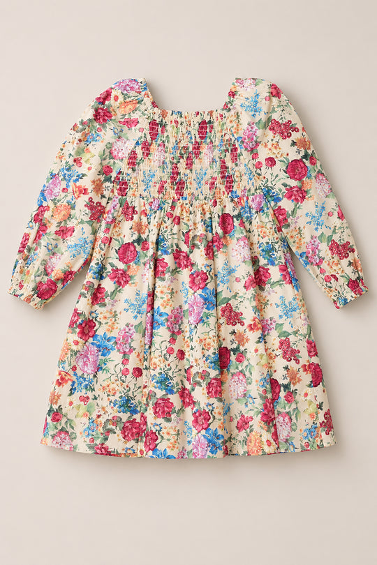 The Mini Adelpha Dress in Autumn Amity Floral by Ivy City Co features long balloon sleeves, a smocked bodice, and a gathered knee-length skirt. Showcasing a vibrant floral print on a cream background, this dress combines playful charm with sophisticated style.
