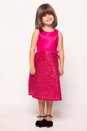 Young girl wearing a pink dress with a sequin skirt on a white background
