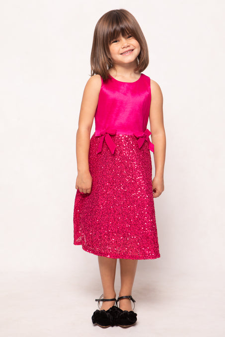 Young girl wearing a pink dress with a sequin skirt on a white background