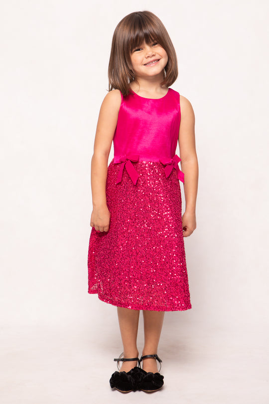 Young girl wearing a pink dress with a sequin skirt on a white background