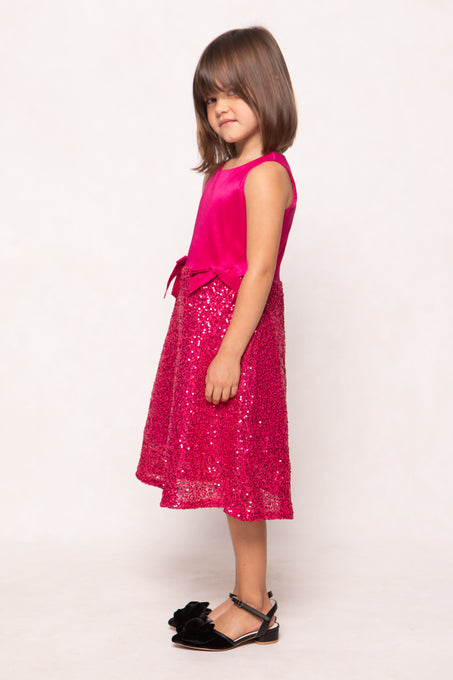Young girl wearing a pink dress with a bow on a white background