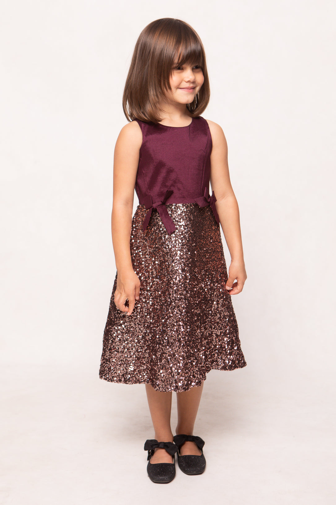 Young girl wearing a burgundy top and sequin skirt on a white background