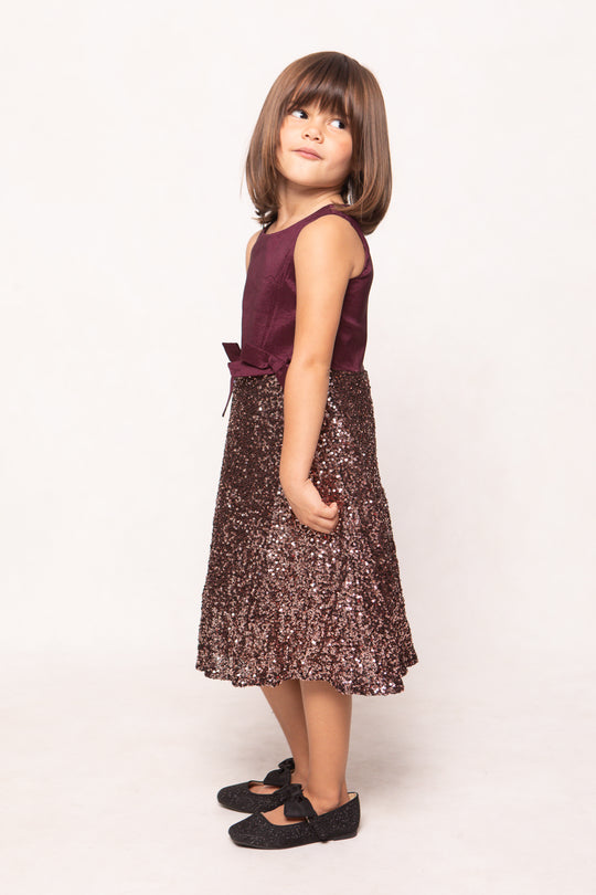 Young girl wearing a purple dress with a floral pattern on a white background