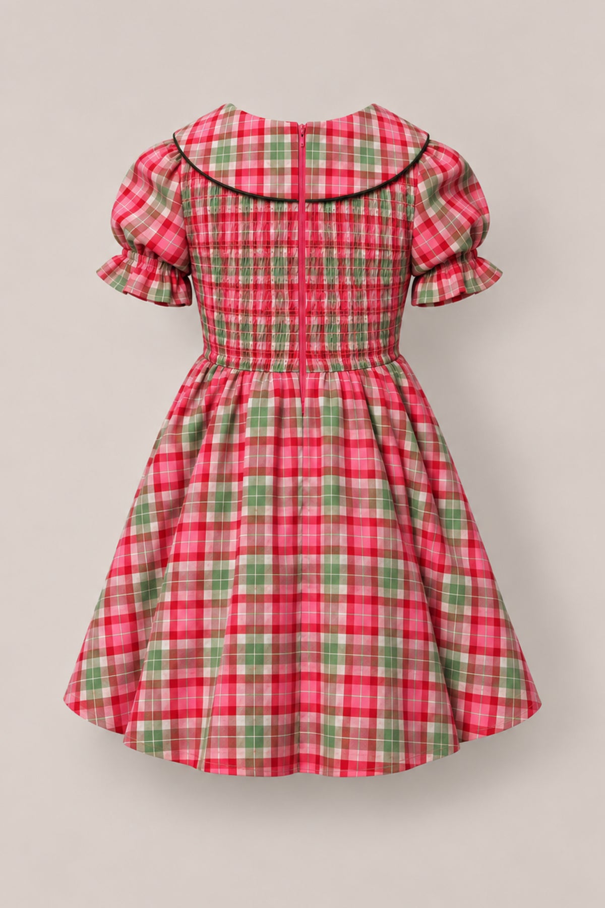 The Mini Alice Dress in Rosewood Tartan by Ivy City Co features a red, green, and white plaid pattern with puffed short sleeves, a Peter Pan collar, a shirred bodice, and a flared skirt. Perfect for mommy-and-me moments, this charming children’s dress is shown against a neutral background for timeless appeal.