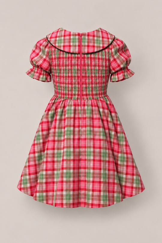 The Mini Alice Dress in Rosewood Tartan by Ivy City Co features a red, green, and white plaid pattern with puffed short sleeves, a Peter Pan collar, a shirred bodice, and a flared skirt. Perfect for mommy-and-me moments, this charming children’s dress is shown against a neutral background for timeless appeal.