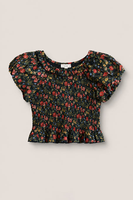 The Mini Annalise Top in Obsidian Vintage Poppies by Ivy City Co is a girls’ black short-sleeve smocked crop top featuring a floral print, ruffled hem, and slight puff sleeves, shown on a plain light background.