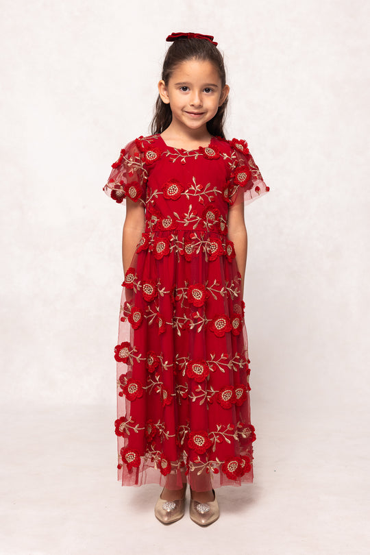 Young girl wearing a red dress with floral patterns on a white background