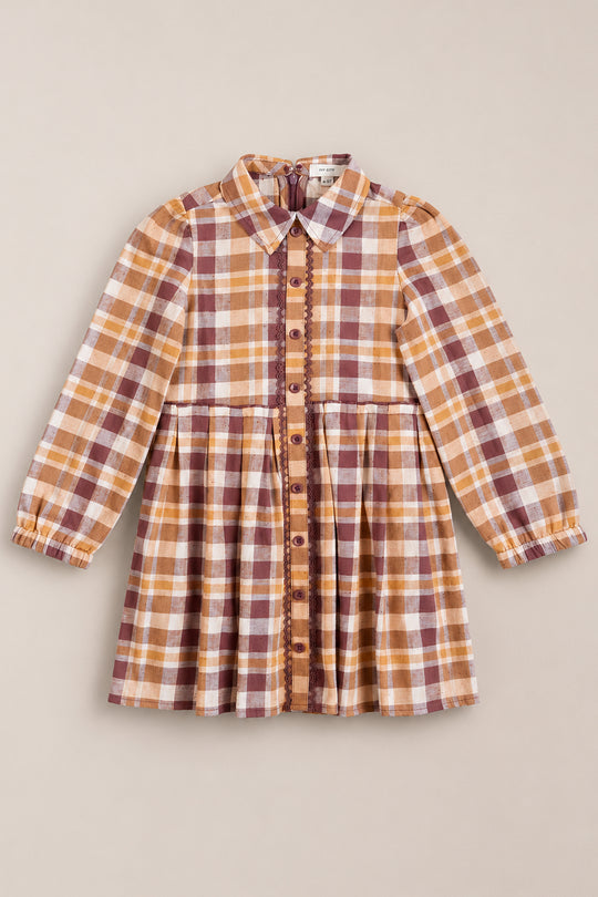 The Ivy City Co Mini Bowie Long Sleeve Dress in Spiced Plaid is a charming children’s dress crafted from cotton, featuring shades of brown, tan, and white. Designed with a button-down front, classic collar, gathered waist, and decorative trim along the buttons.