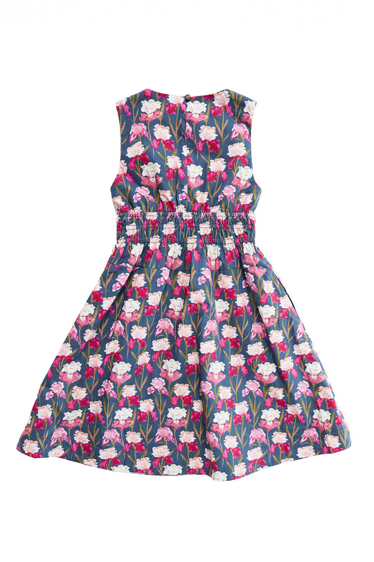 The Mini Carly Dress in Navy Pressed Petals by Ivy City Co is a sleeveless girls' midi dress with a gathered waist, showcasing pink, white, and red florals with green leaves on a navy background. Displayed flat on a white surface.