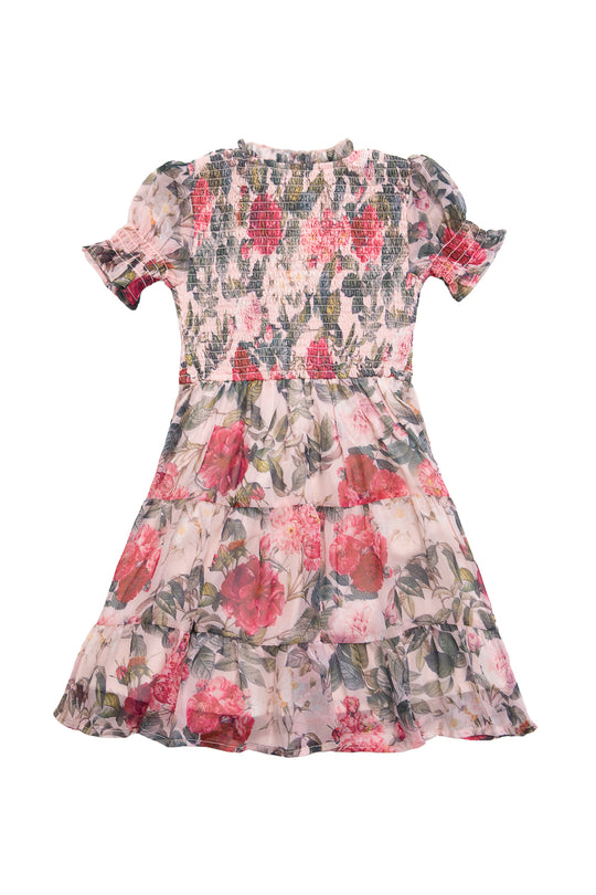The Mini Cordelia Dress in Pink Bloom by Ivy City Co is a knee-length chiffon dress with short puffed sleeves, a smocked bodice, ruffled skirt, and red and green floral pattern on light fabric.