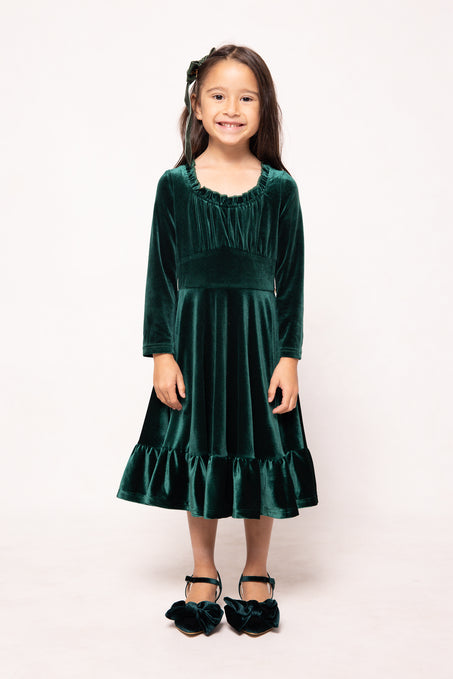Young girl wearing a green velvet dress on a white background