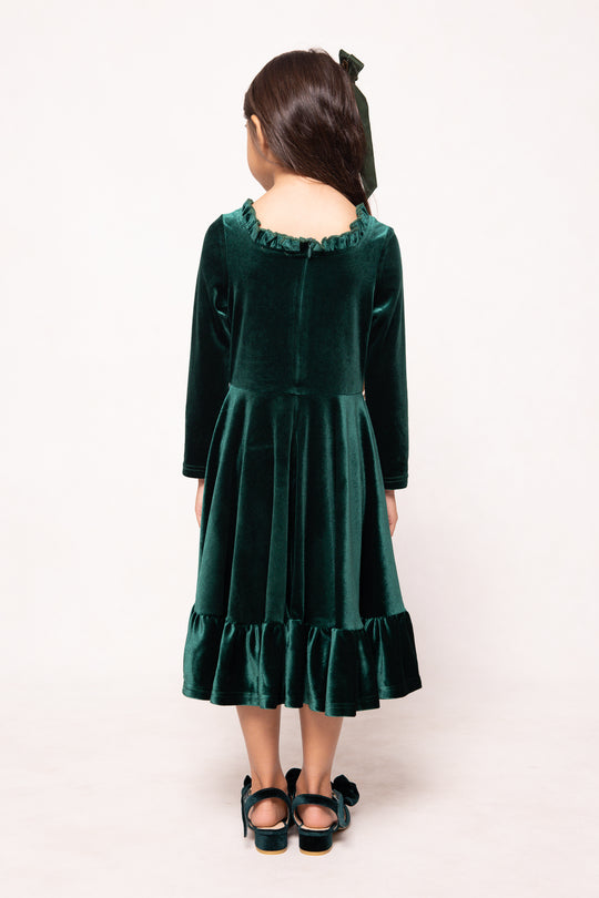 Person wearing a green velvet dress with long sleeves on a white background