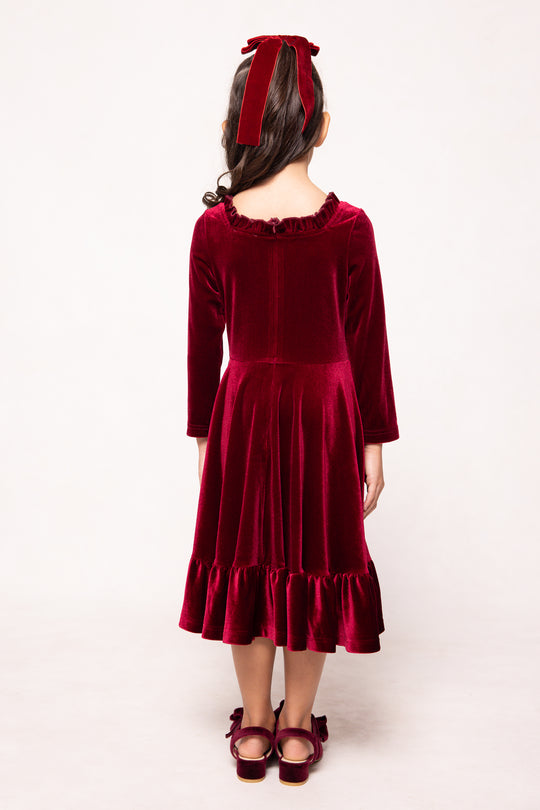 Child wearing a red velvet dress with a bow on a white background