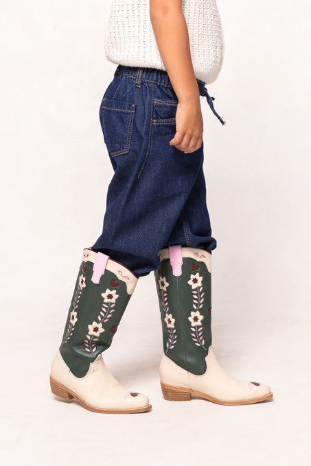 Person wearing floral-patterned green boots with white shoes on a plain background