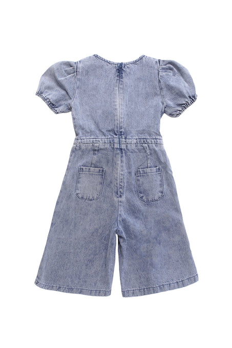 The Ivy City Co Mini Dallas Jumpsuit in Denim is a light blue one-piece for girls with short puff sleeves, wide legs, and two back pockets, displayed flat with the back facing up.