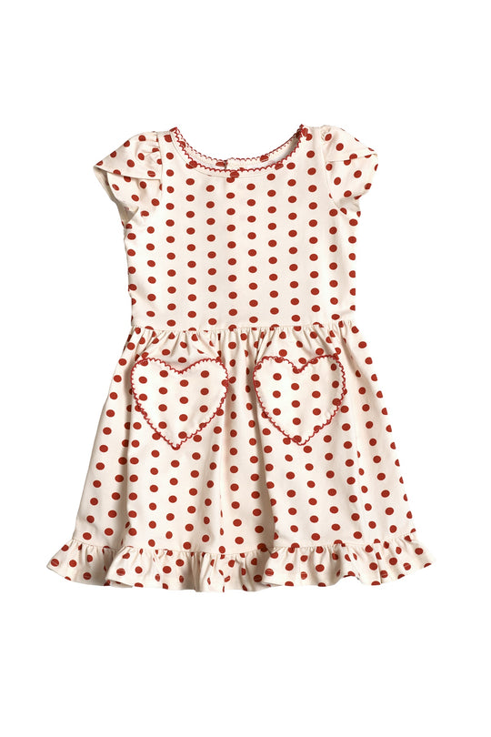 The Mini Dream Play Dress in Red Polka Dot by Ivy City Co is a white, short-sleeve girls' summer dress with red polka dots, ruffled hem, and two heart-shaped pockets—ideal for sunny day play.