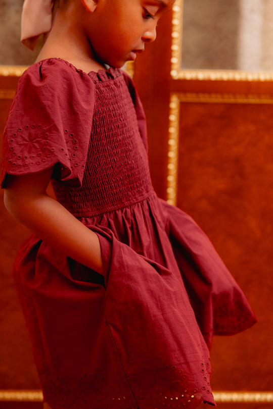 close up of a girl in a burgundy dress with her hands in her pockets