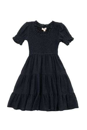The Mini Ellery Dress in Black by Ivy City Co is a kids’ knee-length, short-sleeved dress with a smocked bodice, ruffled round neckline, tiered skirt, and ruffle trim—ideal for matching mom moments.