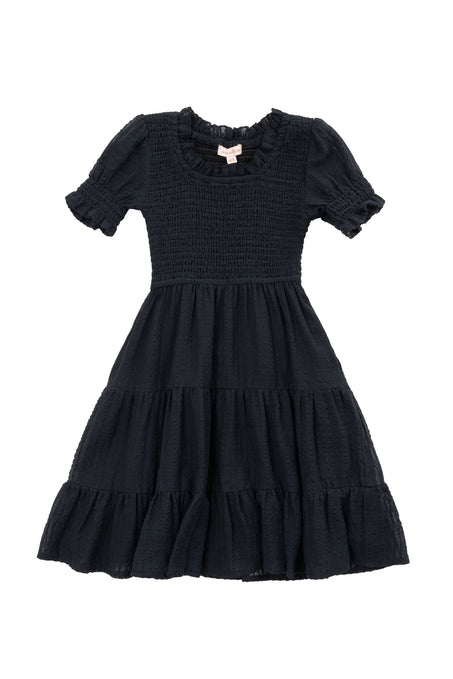 The Mini Ellery Dress in Black by Ivy City Co is a kids’ knee-length, short-sleeved dress with a smocked bodice, ruffled round neckline, tiered skirt, and ruffle trim—ideal for matching mom moments.