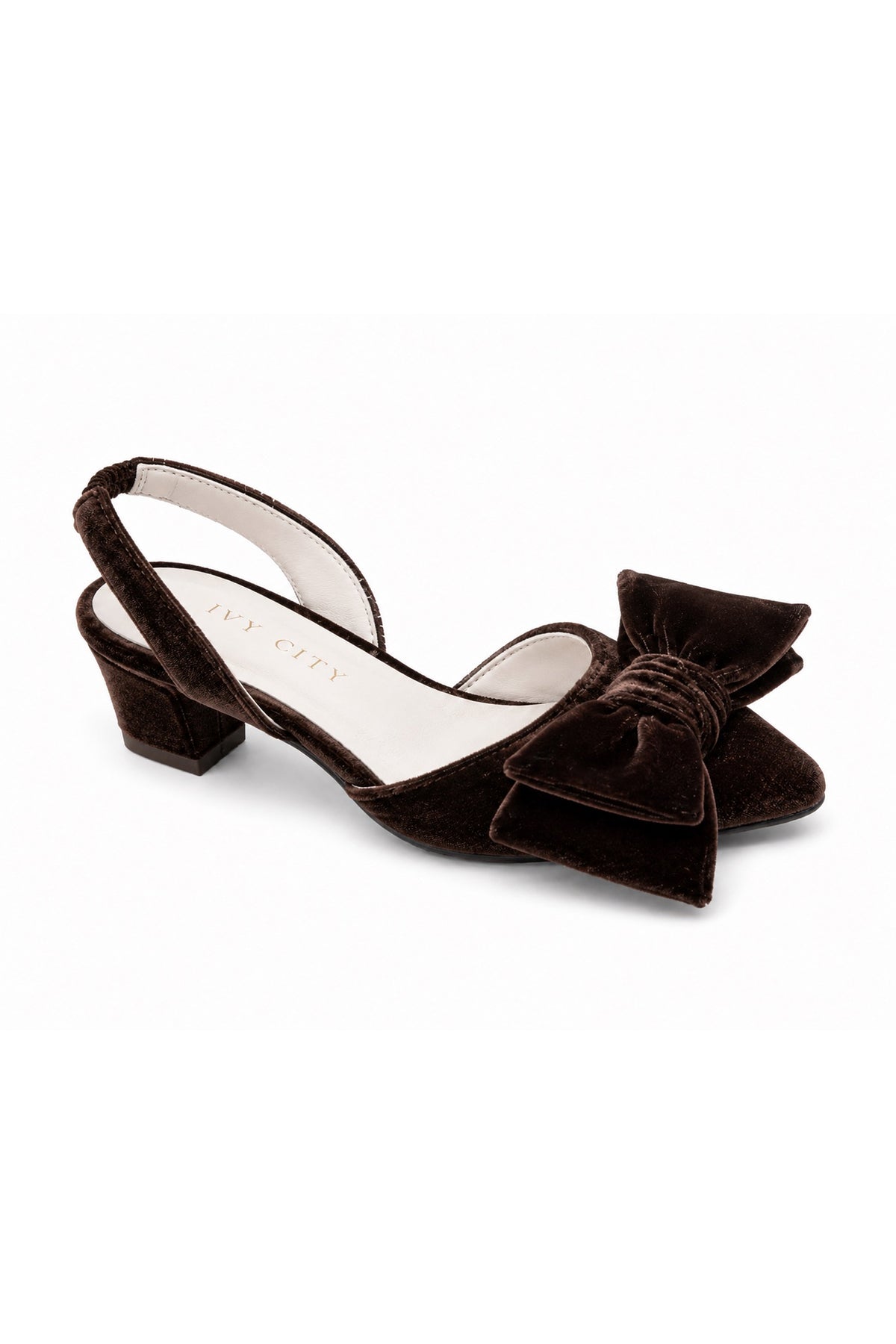 The Mini Eloise Bow Heel in Brown by Ivy City Co is a single dark brown velvet slingback shoe with a low block heel and a large matching bow on the closed toe, featuring a supple leather lining for added comfort, displayed on a white background.