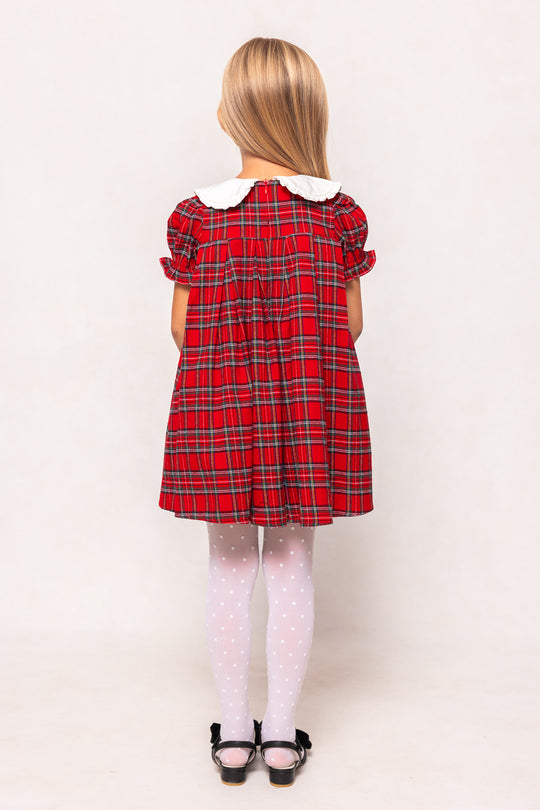 Child wearing a red plaid dress on a white background