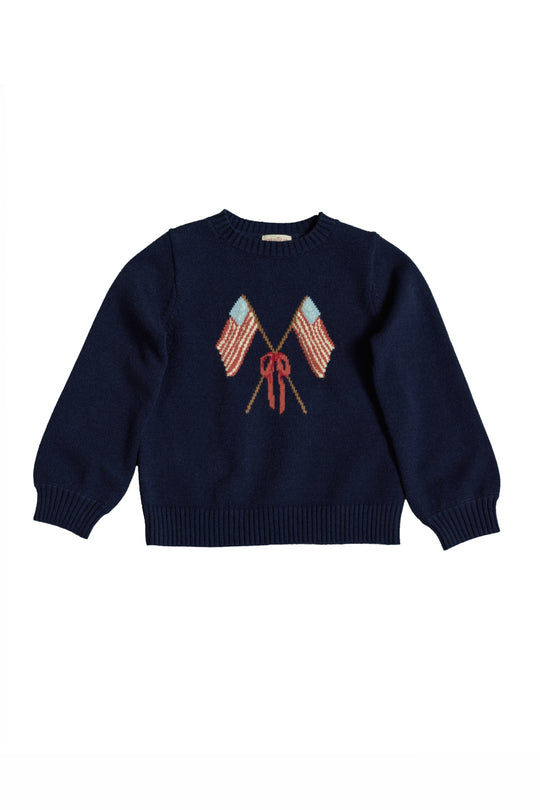 The Ivy City Co Mini Freedom Sweater in Midnight is a navy knit girls' sweater with two crossed American flags and a red bow, perfect for Fourth of July celebrations. Displayed on a white background.